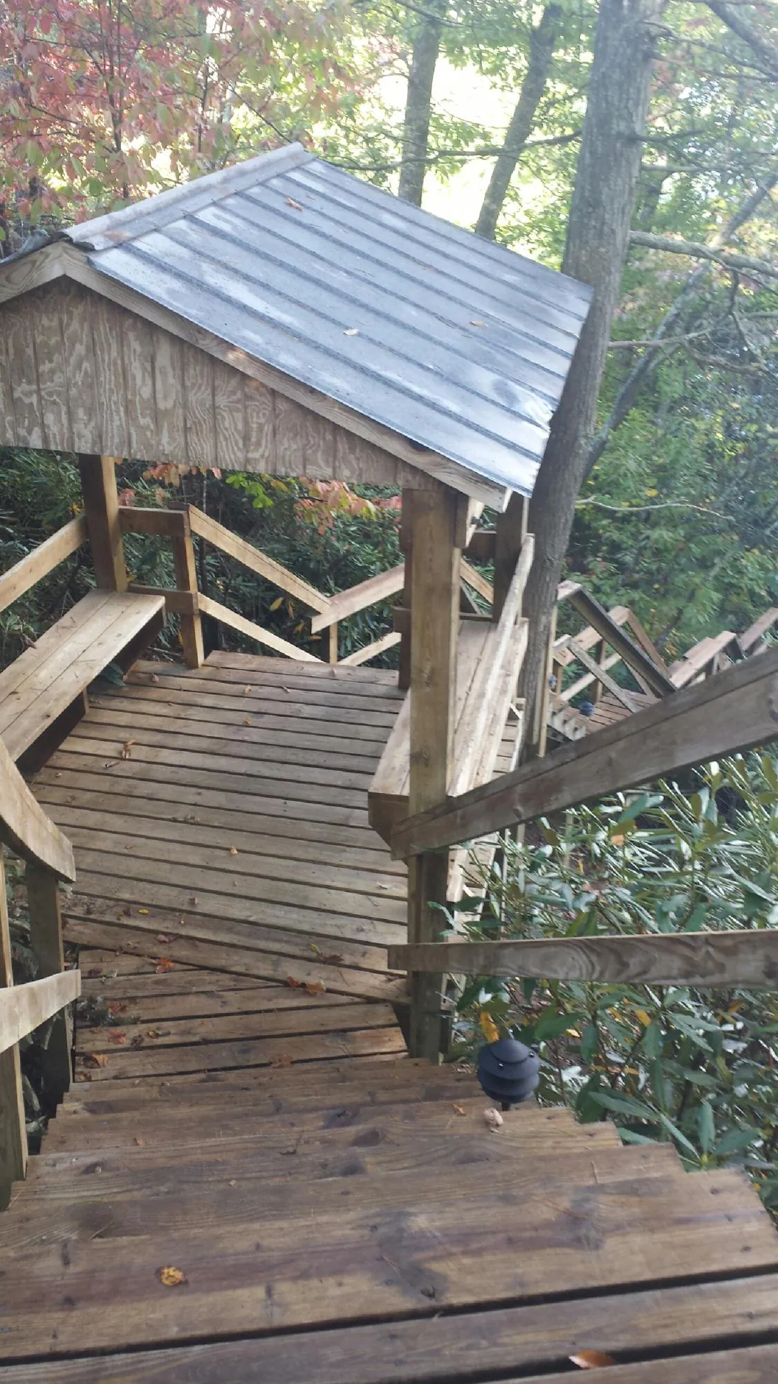 Metal roofed shelter over wooden steps on a wooded walkway — Skylight Repair & Installation work by our crew in Victor